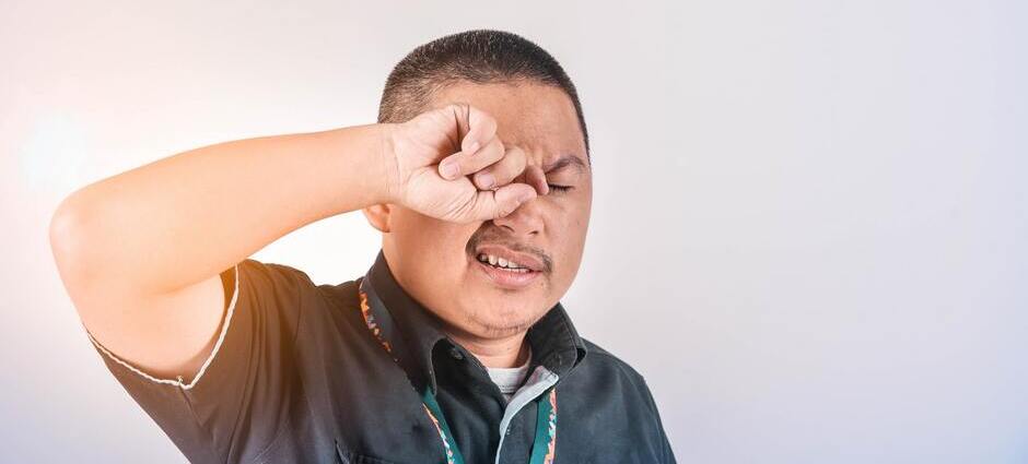 Homem coçando olhos para representar possível transmissão do coronavírus pelos olhos
