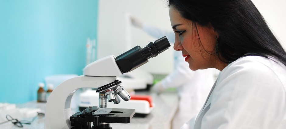 Cientista em laboratório usando o microscópio para investigação de vacina contra o coronavírus